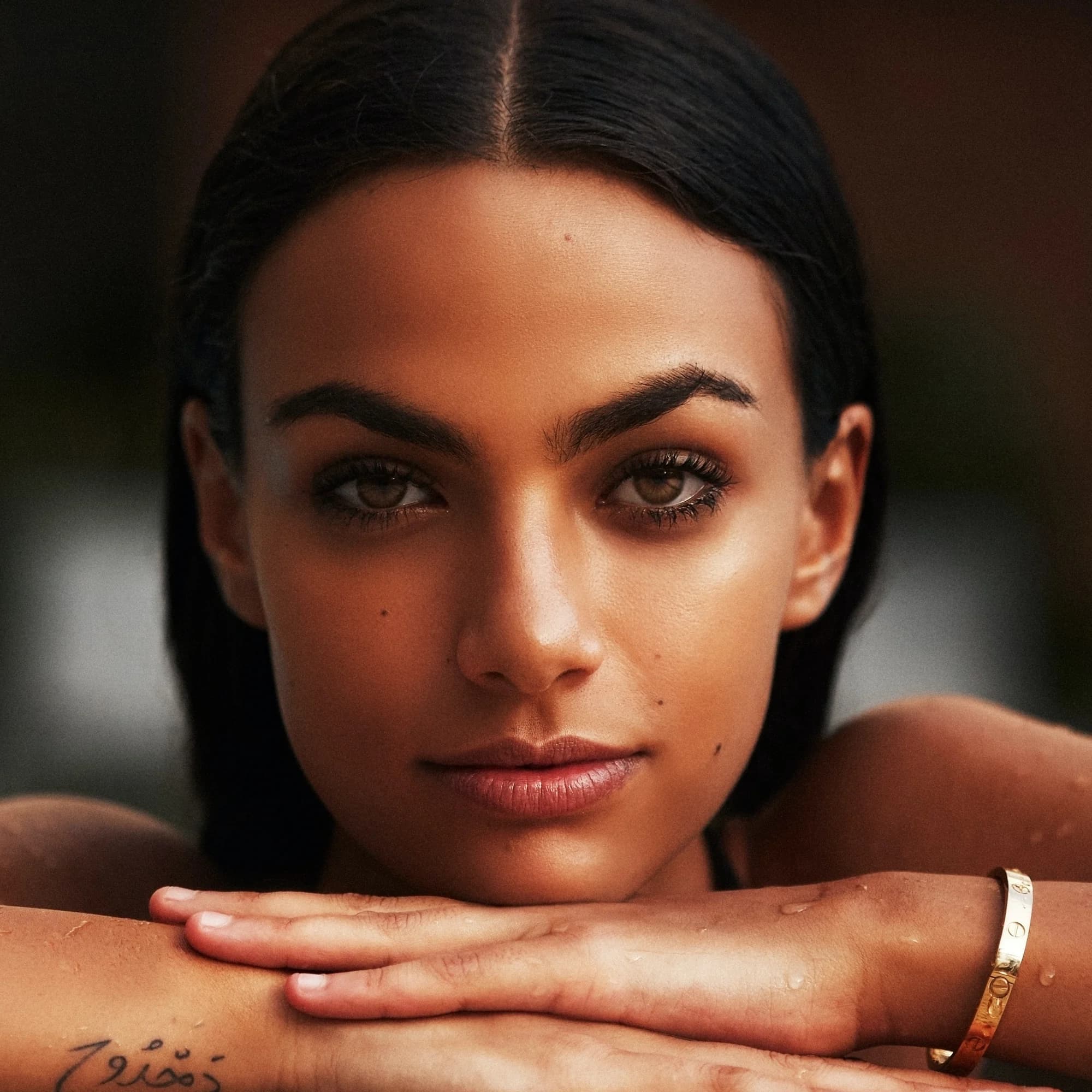 Close editorial portrait of a woman resting her chin on her hands