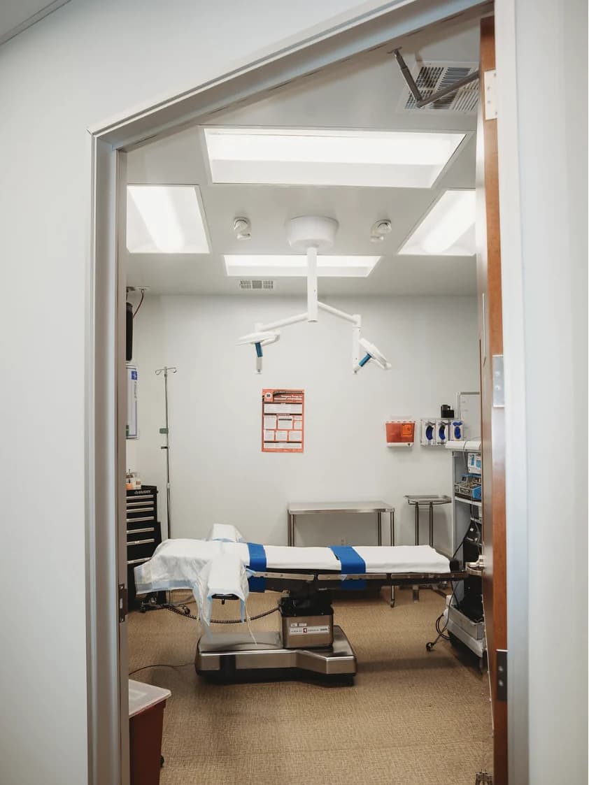 An operating room at Mafi Surgery Center in Fresno, seen through the doorway, with the surgical table draped and the overhead lights folded away